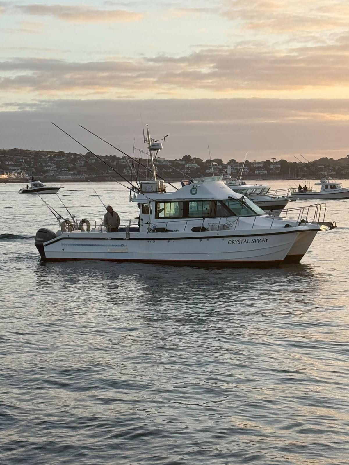 Crystal Spray running out of Falmouth at sunset, rods up in the holders and the skipper on deck